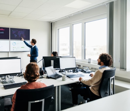 Office With People Reviewing Data On Monitors