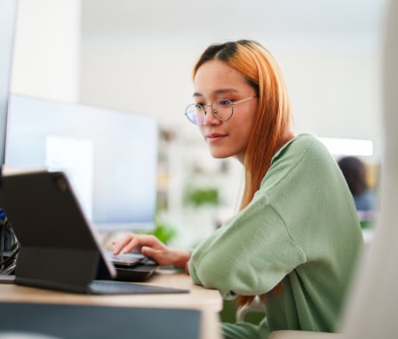 Young woman working on multiple screens at home office