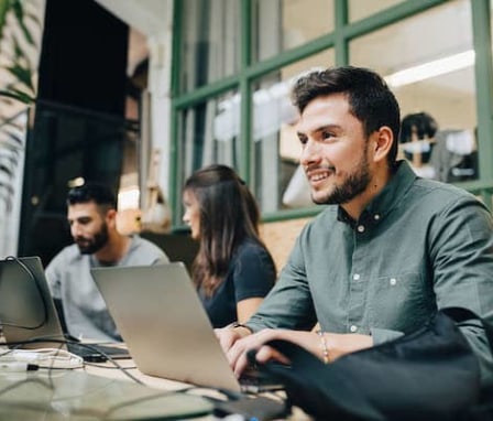 Man smiling and typing on laptop computer