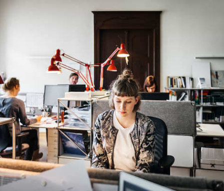 Woman working on computer in an office with colleagues