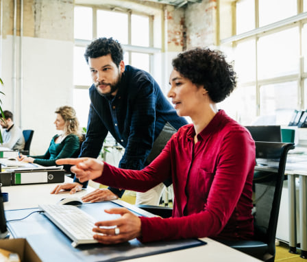 Woman being helped by coworker on computer